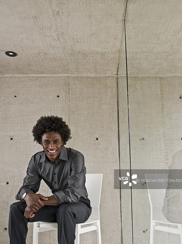 衣着光鲜的年轻男人坐在窗边的椅子上，肖像图片素材