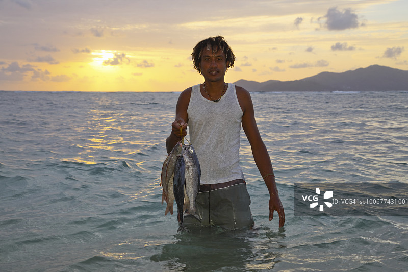 在日落时于海中捕鱼的男人图片素材