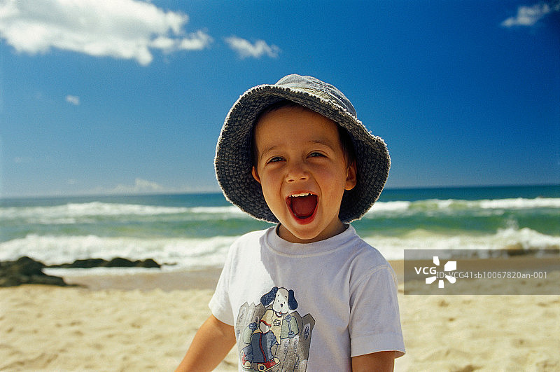 男孩在海滩上大笑，肖像图片素材
