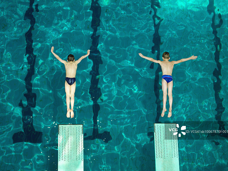两个男孩从起跳台上跳水的高角度视图（8-9岁）图片素材