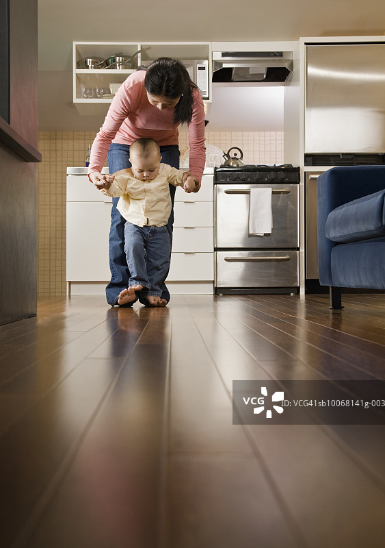 母亲帮助男婴（15-18个月大）走路图片素材