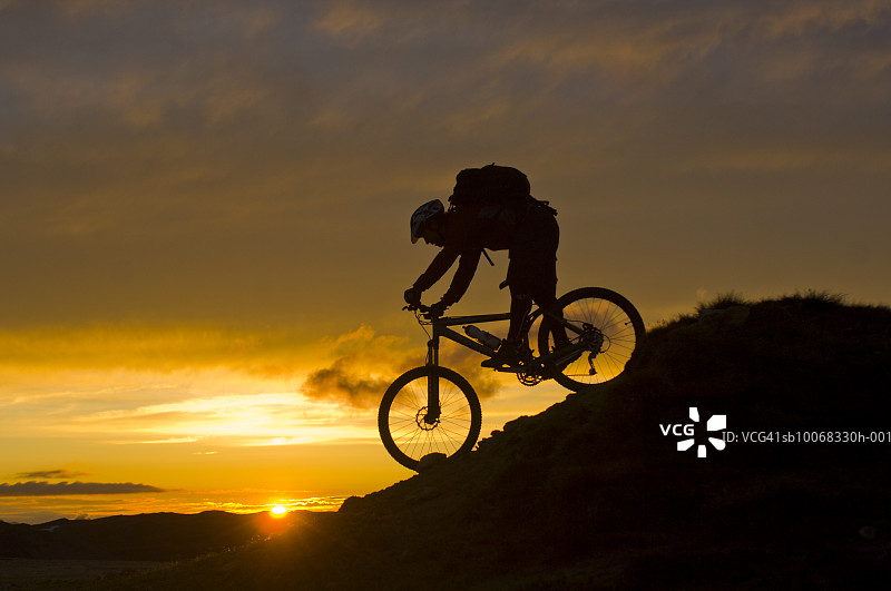 日落时骑山地自行车的男人的剪影图片素材