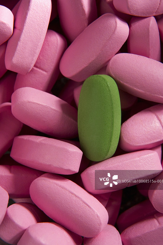 粉色药丸堆里的一颗绿色药丸特写图片素材