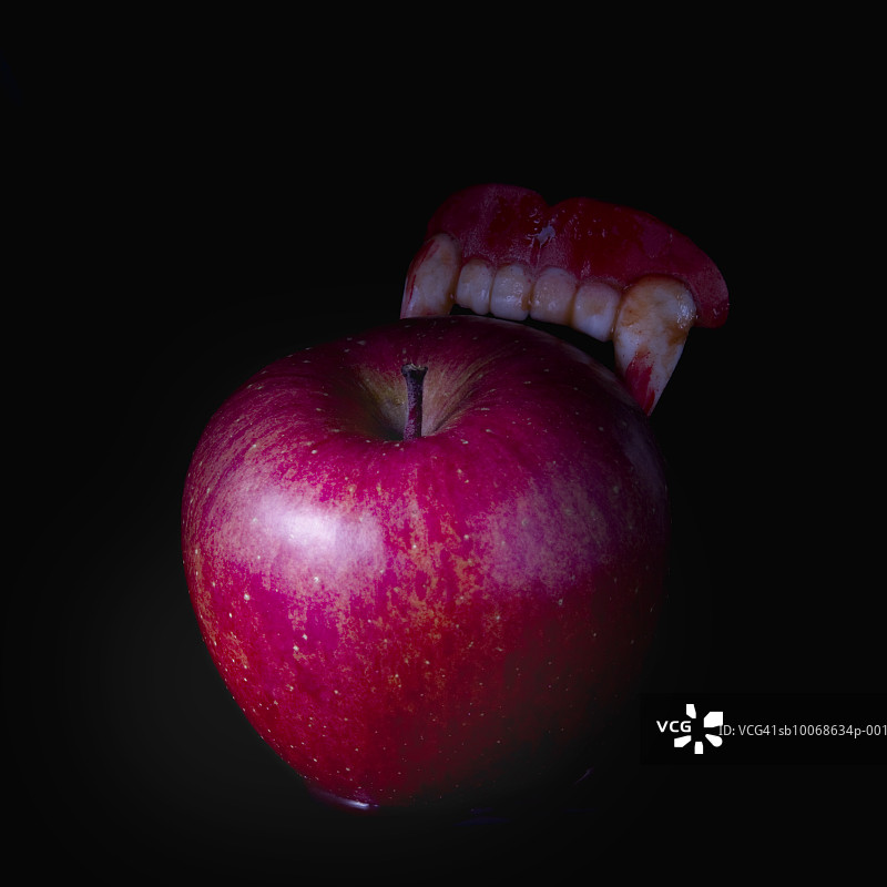 假吸血鬼牙齿和红苹果图片素材