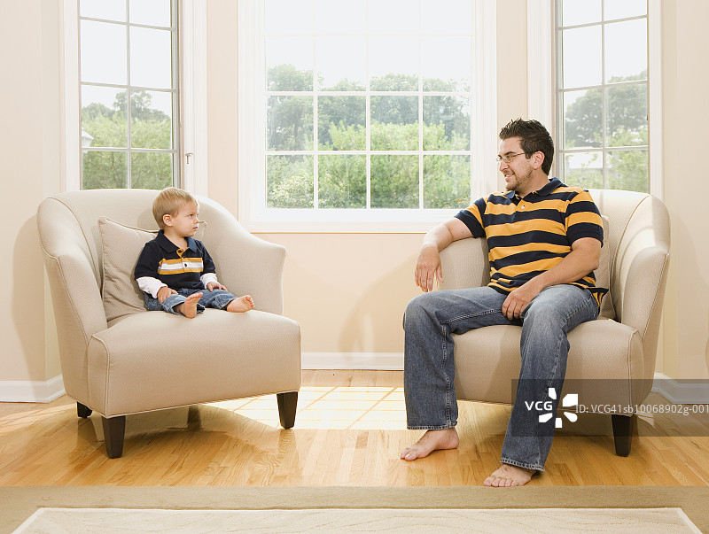 父亲和儿子（2-3岁）坐在扶手椅上互相看着图片素材
