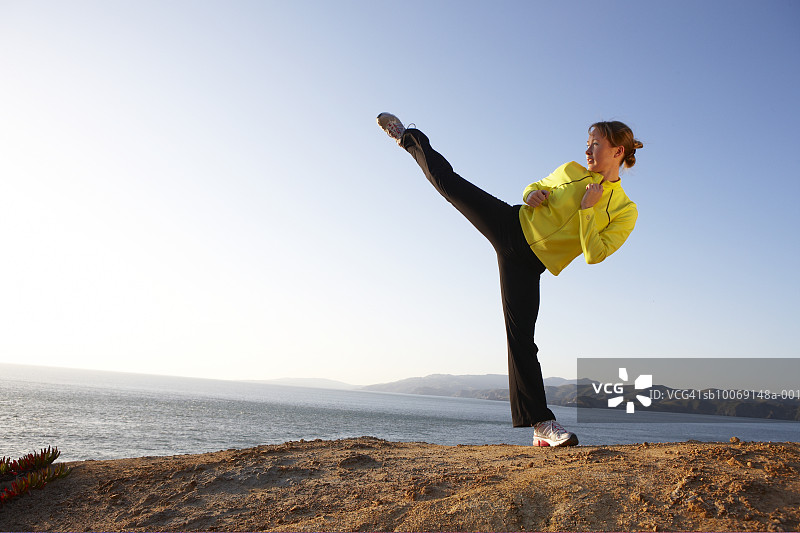 年轻女人在岸边练习高踢腿图片素材