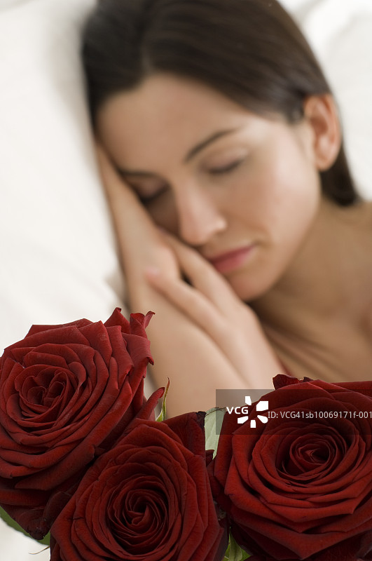 女子睡眠中，聚焦前景的玫瑰花图片素材