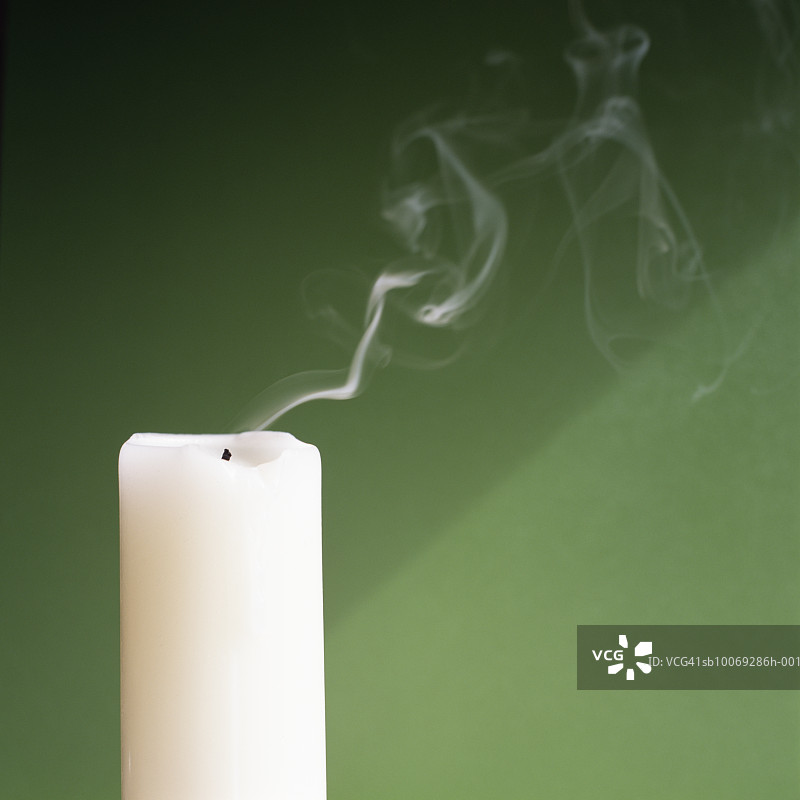 绿色背景下的冒烟蜡烛，工作室拍摄图片素材