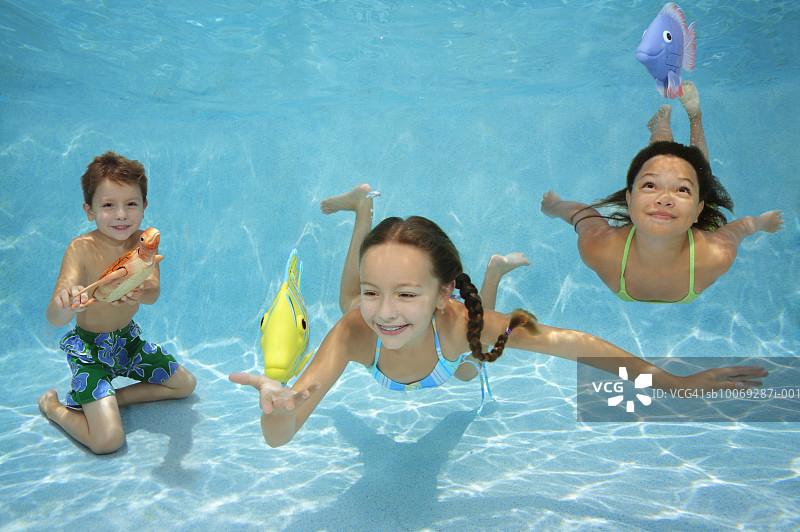 儿童在水下与玩具鱼一起游泳图片素材