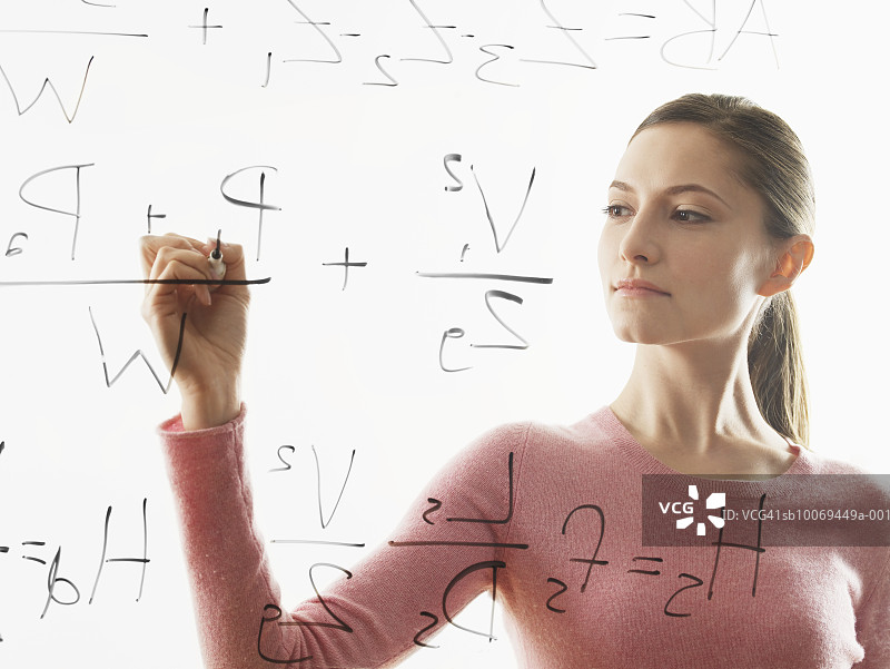 年轻女人在玻璃上写方程式图片素材