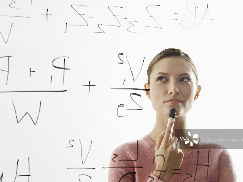 年轻女人在玻璃上计算公式图片素材