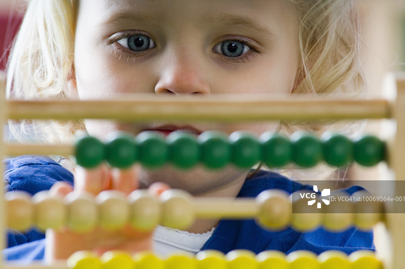 4-5岁女孩在教室里使用算盘，特写图片素材