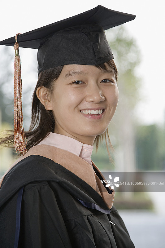 身穿毕业礼服的年轻女子微笑特写侧面照图片素材