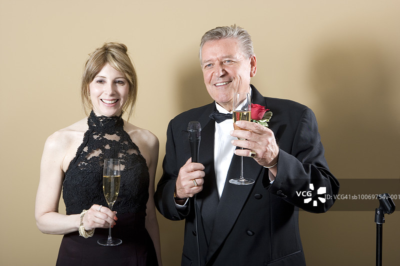 穿着讲究的夫妇手持香槟和麦克风的影棚照图片素材