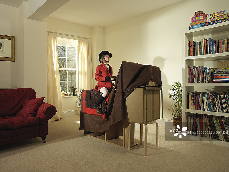 女孩（8-9岁）假装骑着家具和毯子做的马图片素材