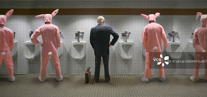 商人和四个穿着兔子服装的男人站在小便池旁，后视图（数字合成）图片素材