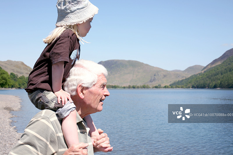 老年男人和孙女（2-3岁）在湖边，孙女坐在肩膀上图片素材
