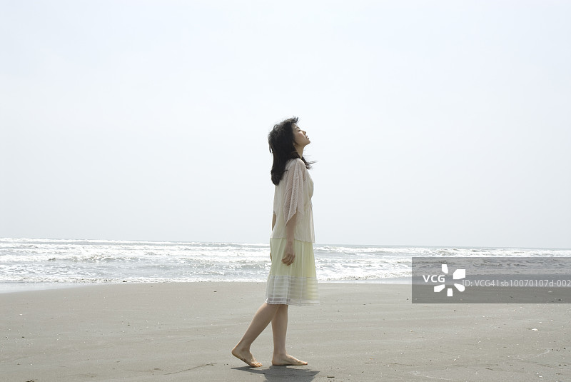 海滩上闭着眼睛的年轻女人图片素材