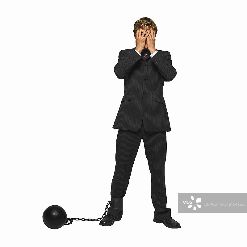 商人腿上绑着锁链，用手捂着脸图片素材
