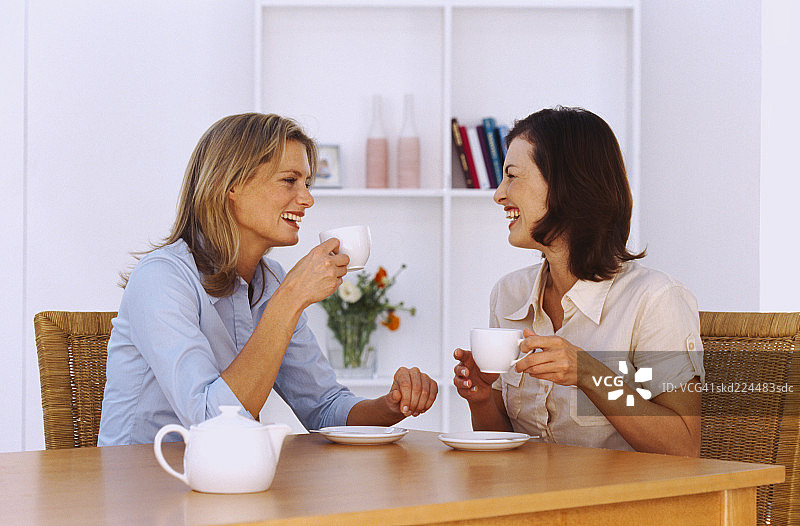 两位年轻女人在餐桌旁喝茶图片素材