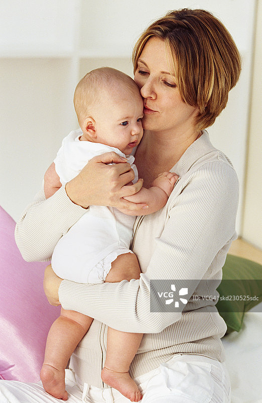 母亲抱着男婴（6-12个月大）的特写图片素材