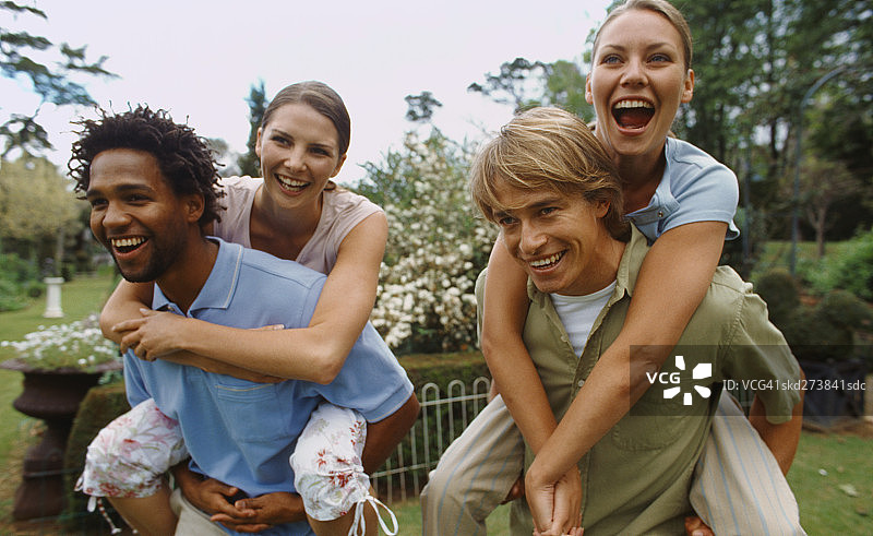 两对情侣快乐地玩骑 piggyback 游戏图片素材