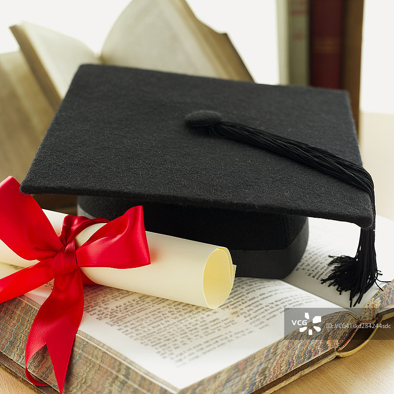 毕业帽、带丝带的文凭和教科书特写图片素材