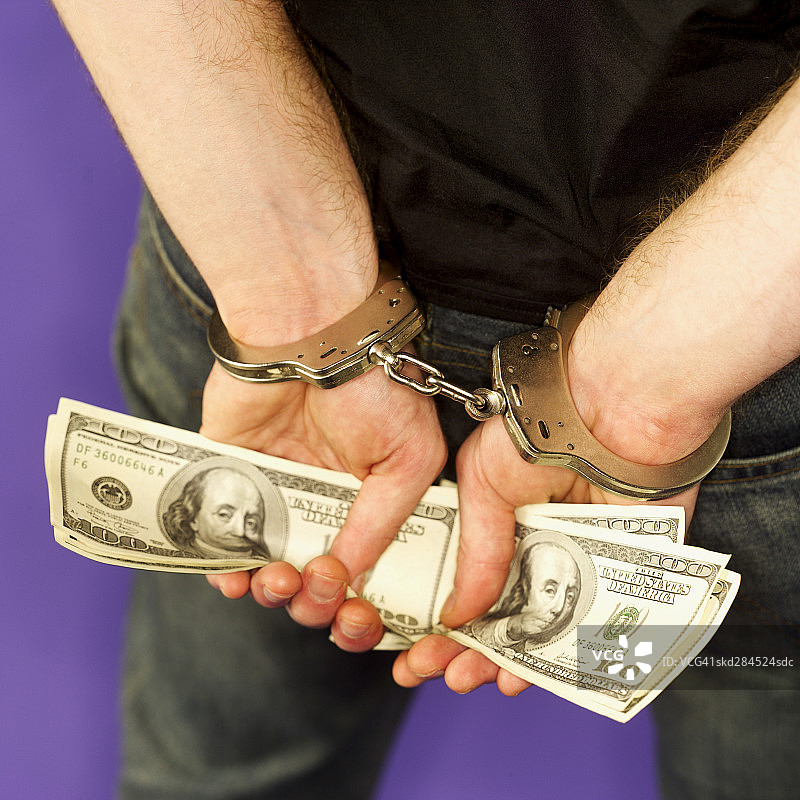 男子戴手铐持美元钞票的背部特写图片素材