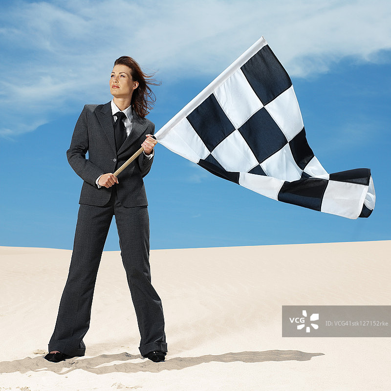 在沙漠中手持方格旗的年轻女人图片素材