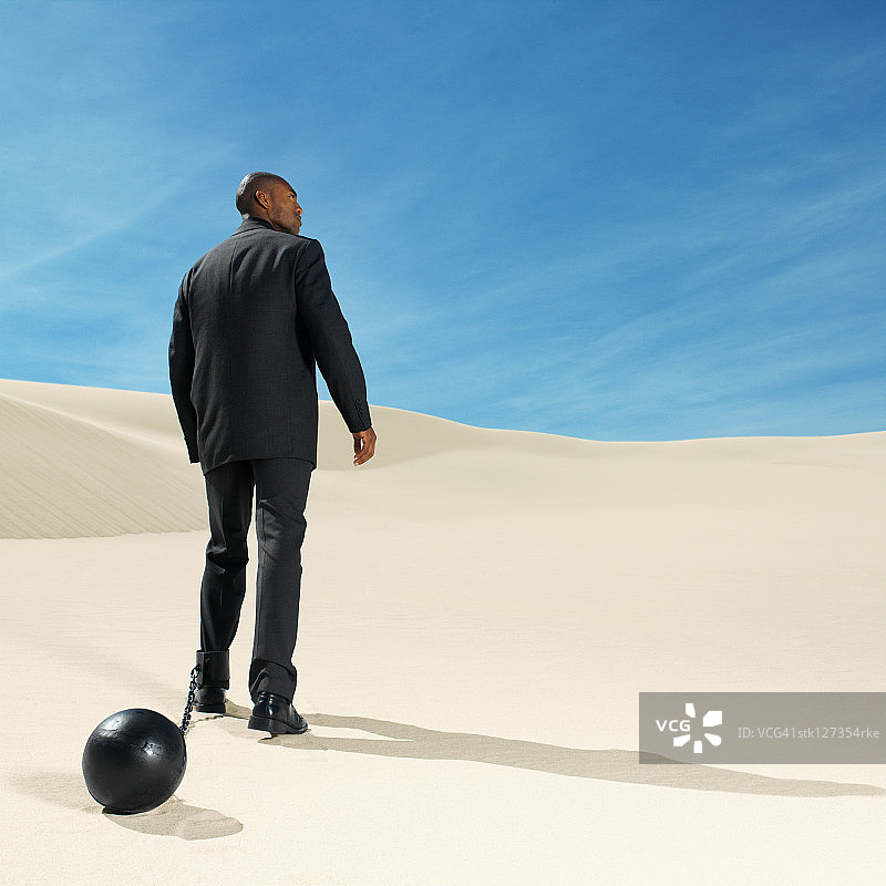 沙漠中戴着镣铐的商人背影图片素材