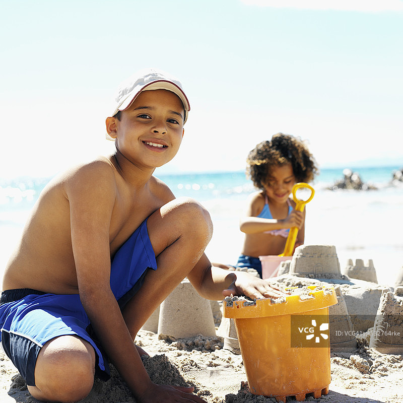 海滩上制作沙堡的姐弟特写图片素材