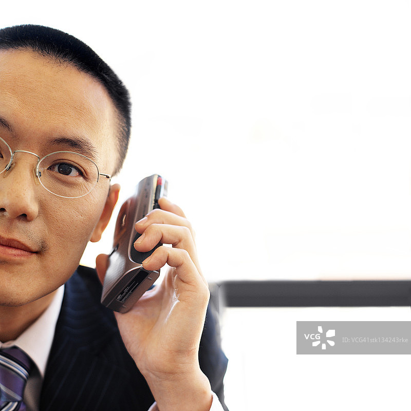 拿着卡式录音机贴在耳朵上的男商人肖像图片素材