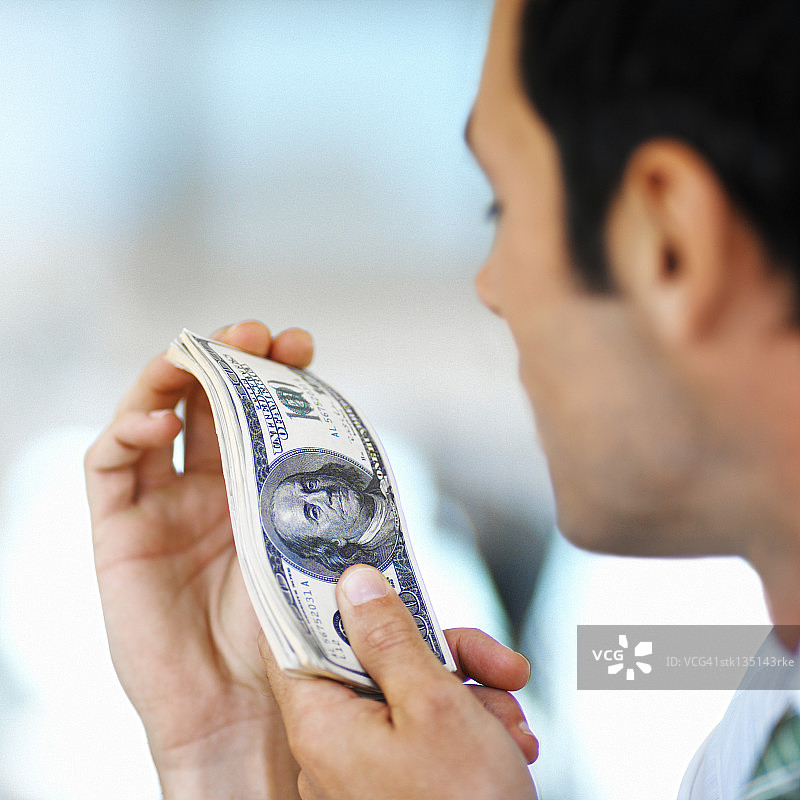 男人手持一叠百元美钞特写图片素材