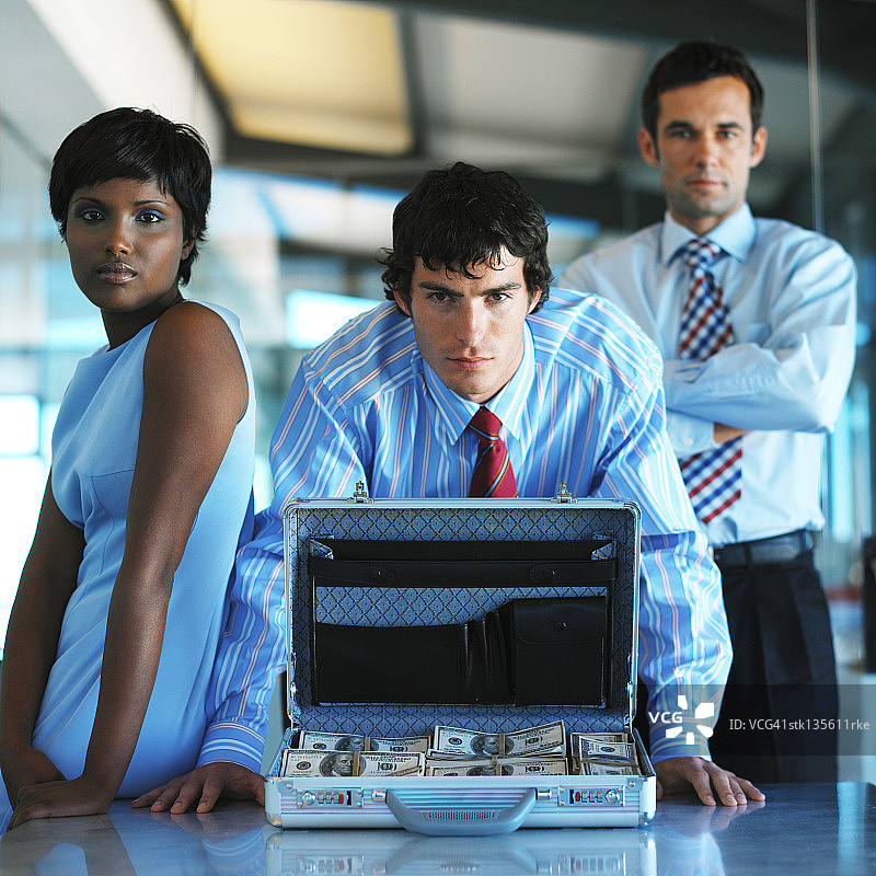 打开的装满钱的公文包后面的商务人士肖像图片素材