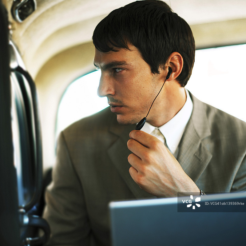 侧面轮廓：商务男士坐在车内，使用耳机交谈图片素材