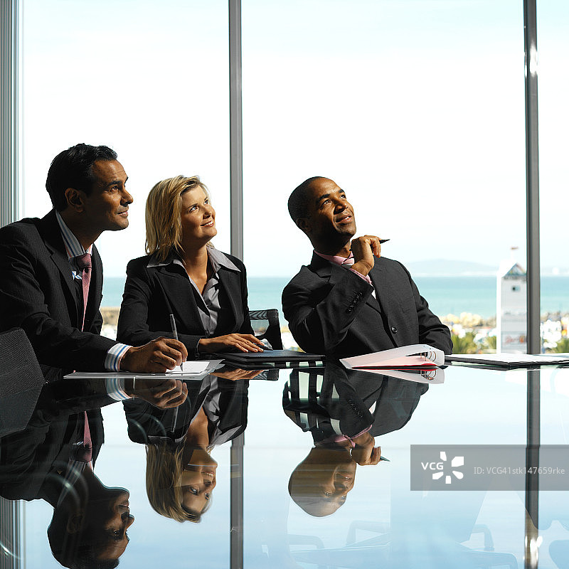 三位商务人士坐在会议桌旁向上看的侧视图图片素材