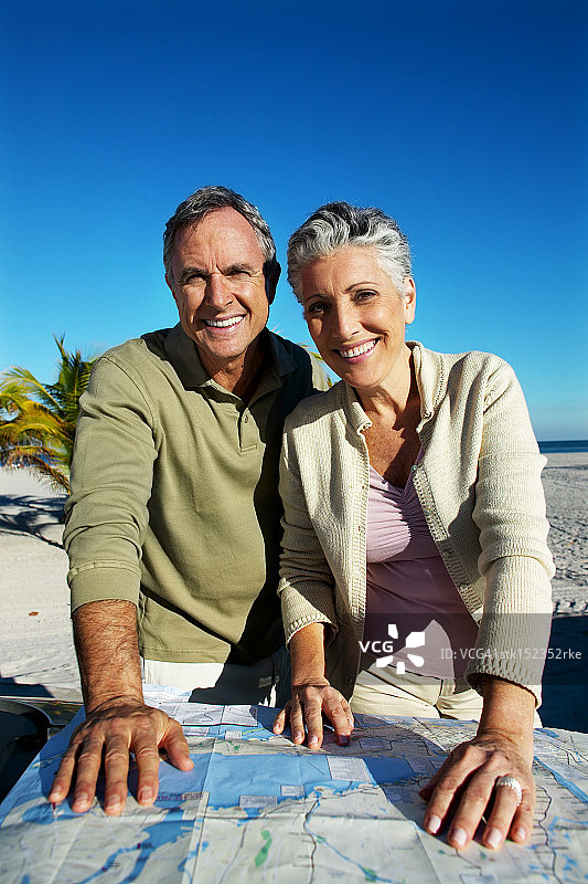 在海滩上阅读地图的成熟夫妇肖像图片素材