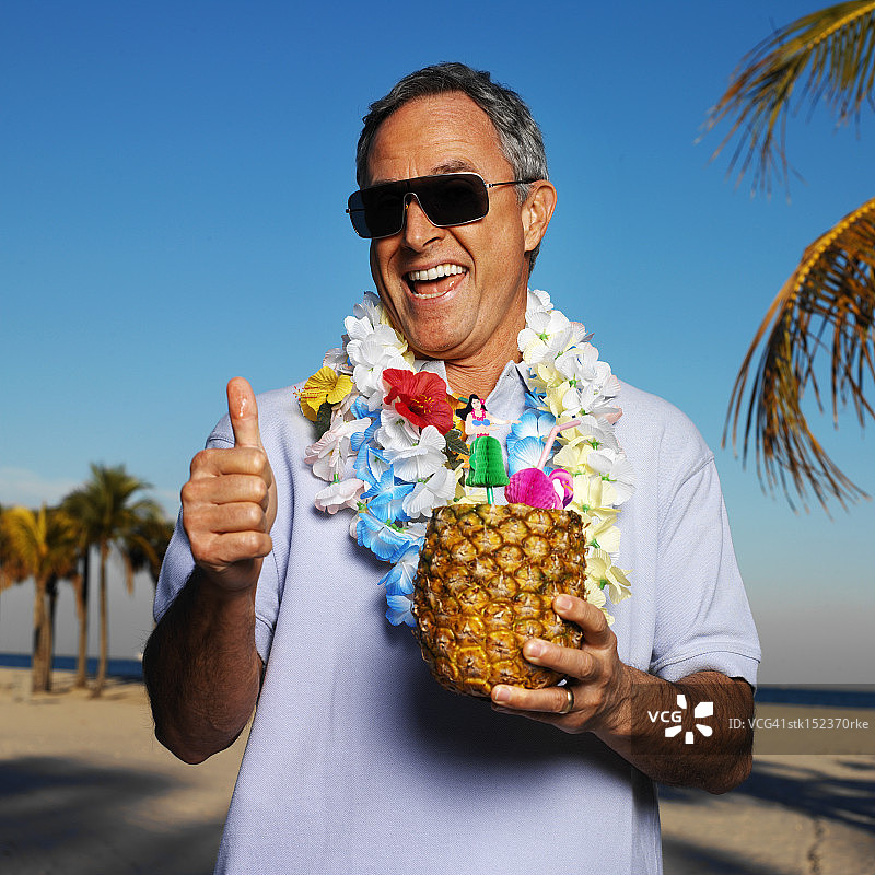 一位享受菠萝鸡尾酒的度假老人肖像图片素材