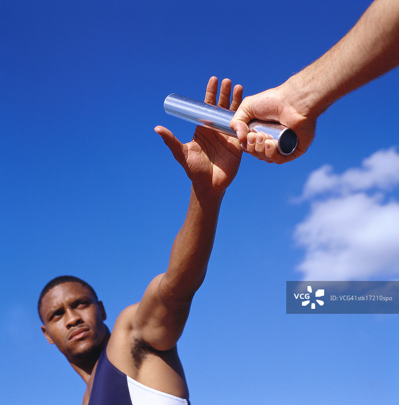 两名年轻男子在接力赛中交换接力棒的仰视角度图片素材