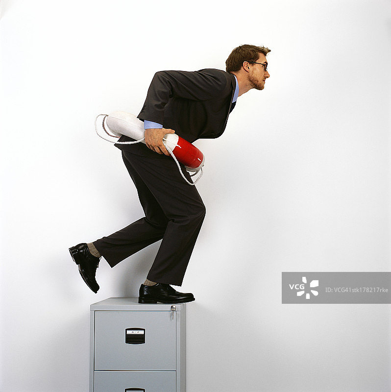 年轻男人站在文件柜顶上，穿着救生圈图片素材