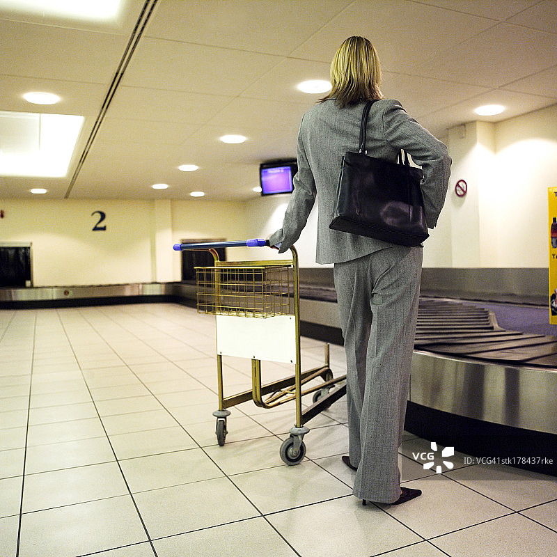 女子靠在行李车上等待行李图片素材