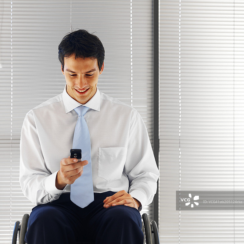 坐在轮椅上看手机的商务男士图片素材