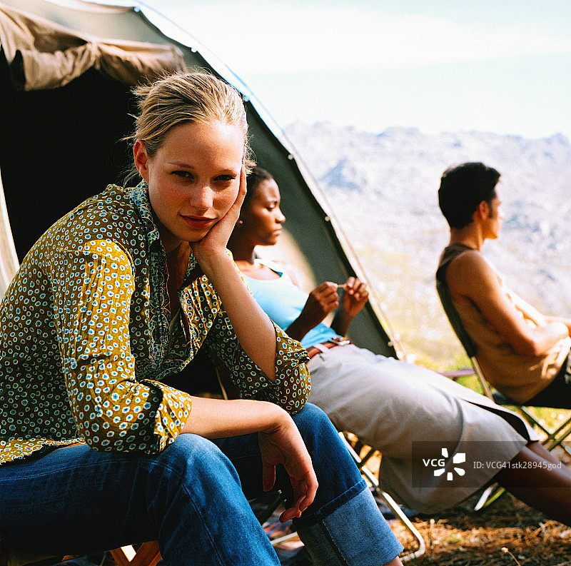 在露营帐篷外与朋友们坐在一起的女人的侧面轮廓图片素材