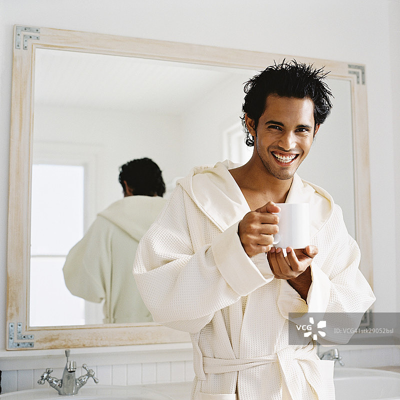穿着浴袍手拿杯子的年轻男人肖像图片素材