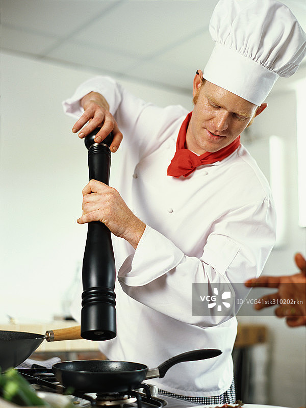 厨师在厨房里拿着胡椒研磨器图片素材