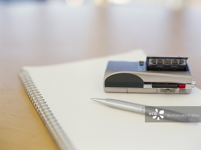 办公室场景：钢笔和个人立体声在螺旋笔记本上图片素材