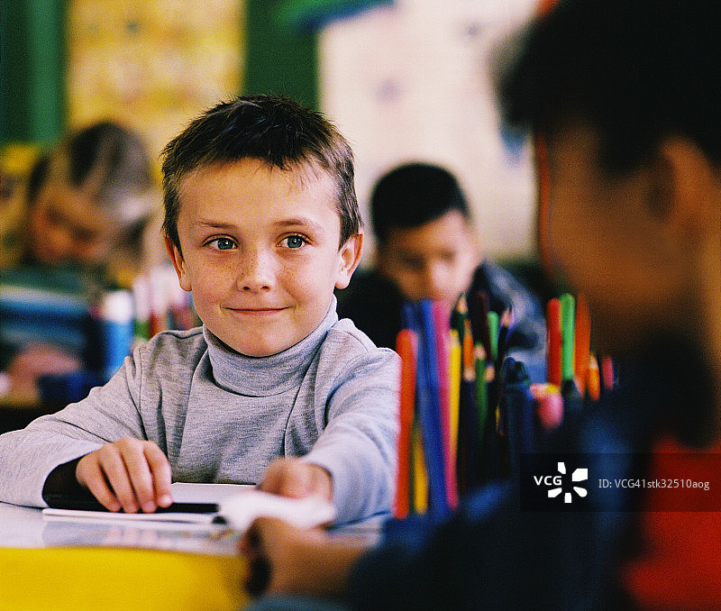 课堂上传纸条的男孩肖像（8-10岁）图片素材