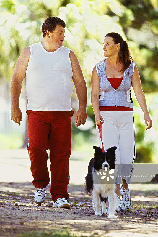 中年夫妇在公园里遛狗图片素材