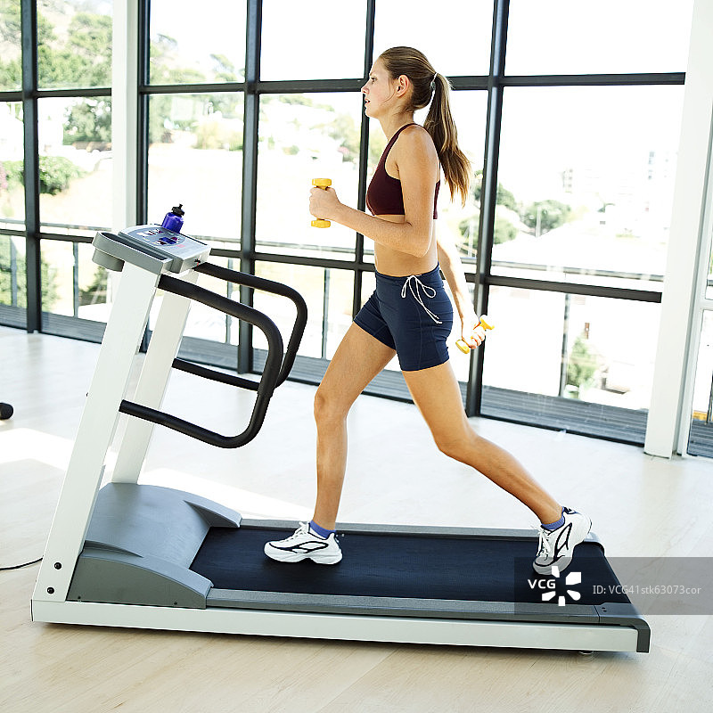 年轻女人在跑步机上慢跑图片素材