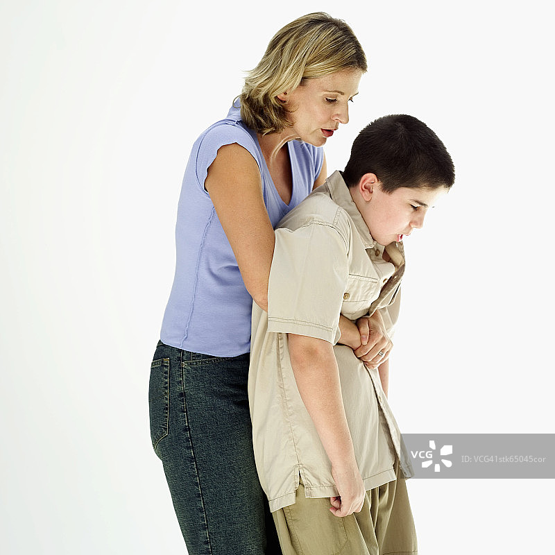 侧视图：女人对10-12岁的男孩进行海姆立克急救图片素材